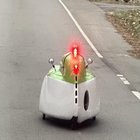 ​2-foot-ish Air-fryer-looking white-plastic thing with two metallic orbs and flashing lights moving on the road
