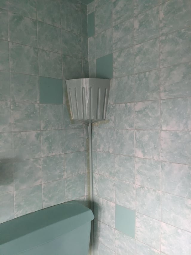 ​Have just bought a house with an original 1960s bathroom (UK) but this corner container above the loo is stumping everyone. It isn’t plumbed into the toilet and the pipe disappears into the wall at floor level. Any ideas?