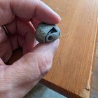 Irregular grey, stony object with circular holes and a shiny inclusion, found off the cost of an Aleutian island.