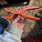 Orange grabber thing? Two rubber pads and two hinge points, hand grip and a hanging hole, maybe?