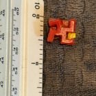 ​Small red plastic clip (~1/2 inch) with yellow hinged tab and four hooked arms, lightweight injection-molded plastic, found in grass in front yard