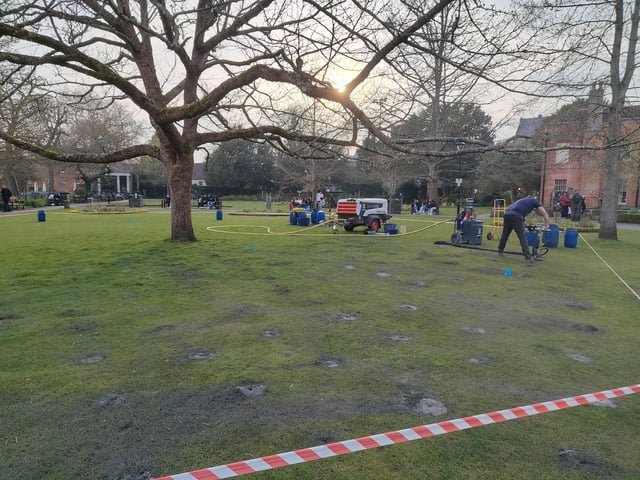 ​Noisy machine pumping grey dust under the turf in city park