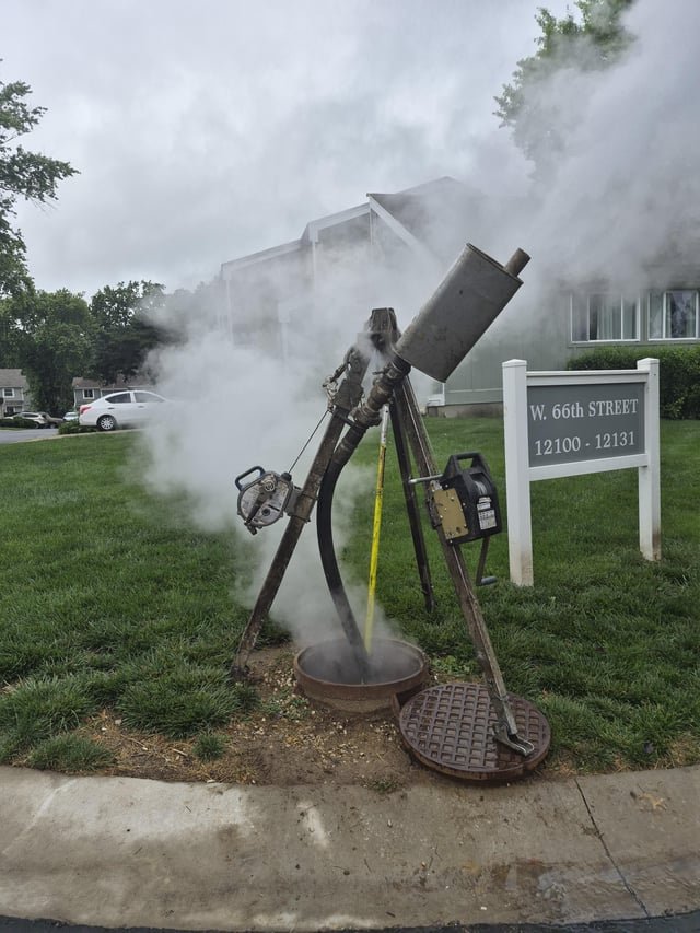 ​Some kind of a tripod with a muffler on it shooting at steam over a sewer in my neighborhood