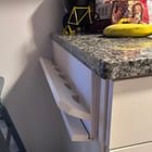 ​Wooden painted rack-like thing attached to the side of a kitchen cabinet below the counter